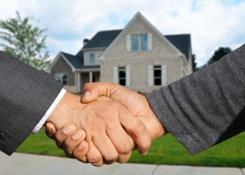 personnes se serrant la main devant une maison après promesse de vente